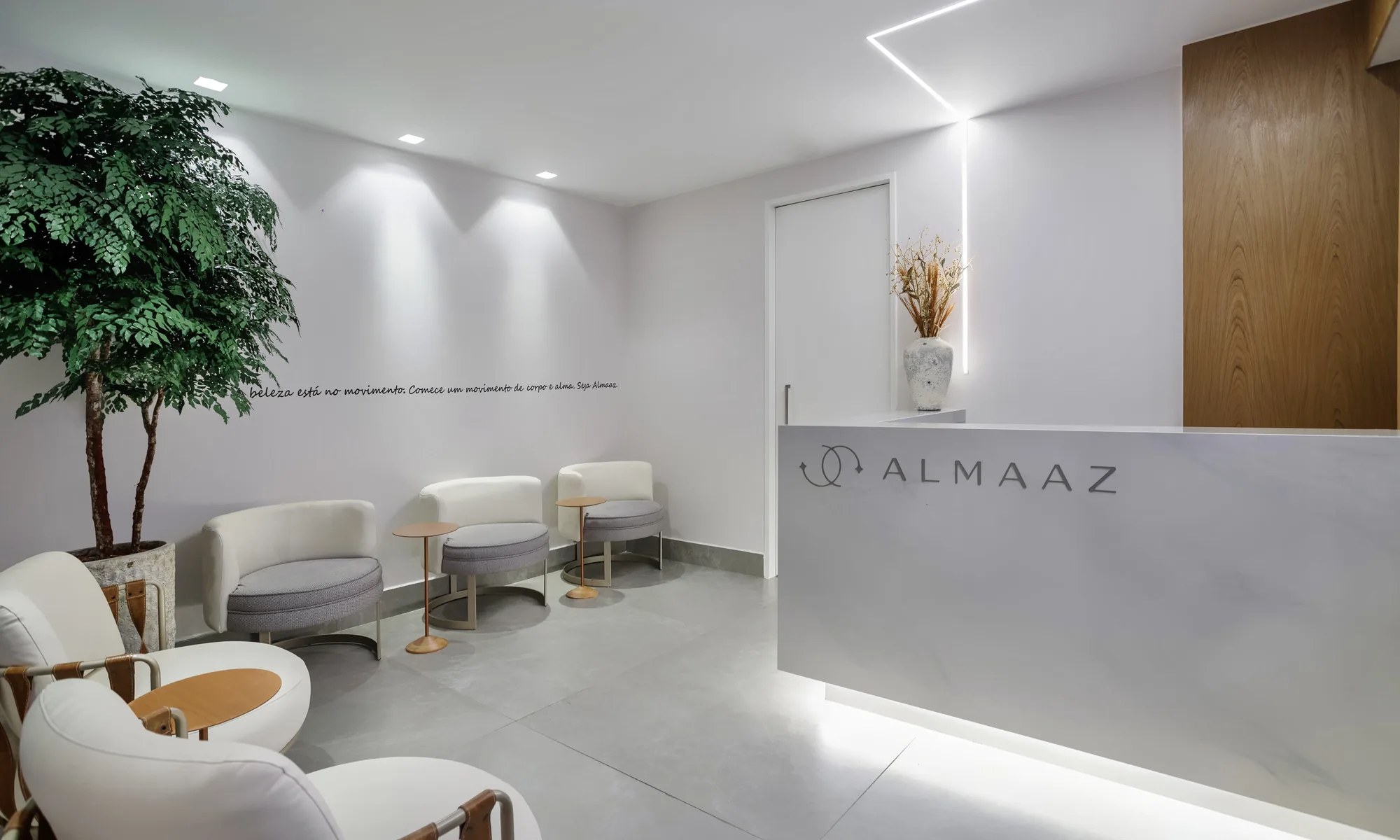 Reception and waiting area of Clínica Almaaz in Leblon, with white armchairs and the Almaaz logo on the counter