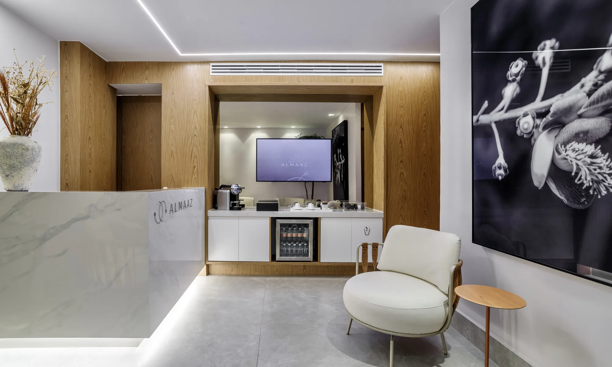 Clínica Almaaz reception with marble counter, coffee corner and botanical artwork